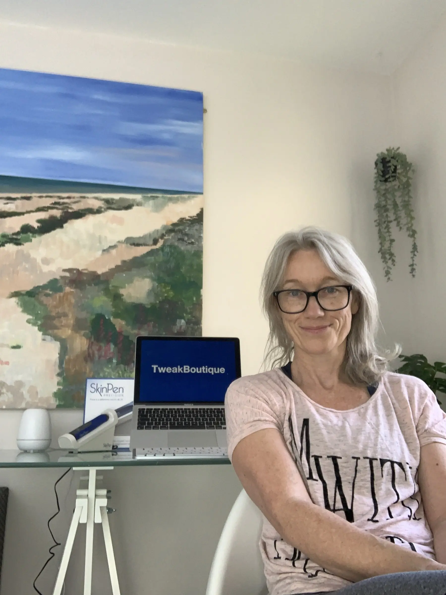 Dr Julie Ridley at her desk in the TweakBoutique clinic, beneath a painting of the beach